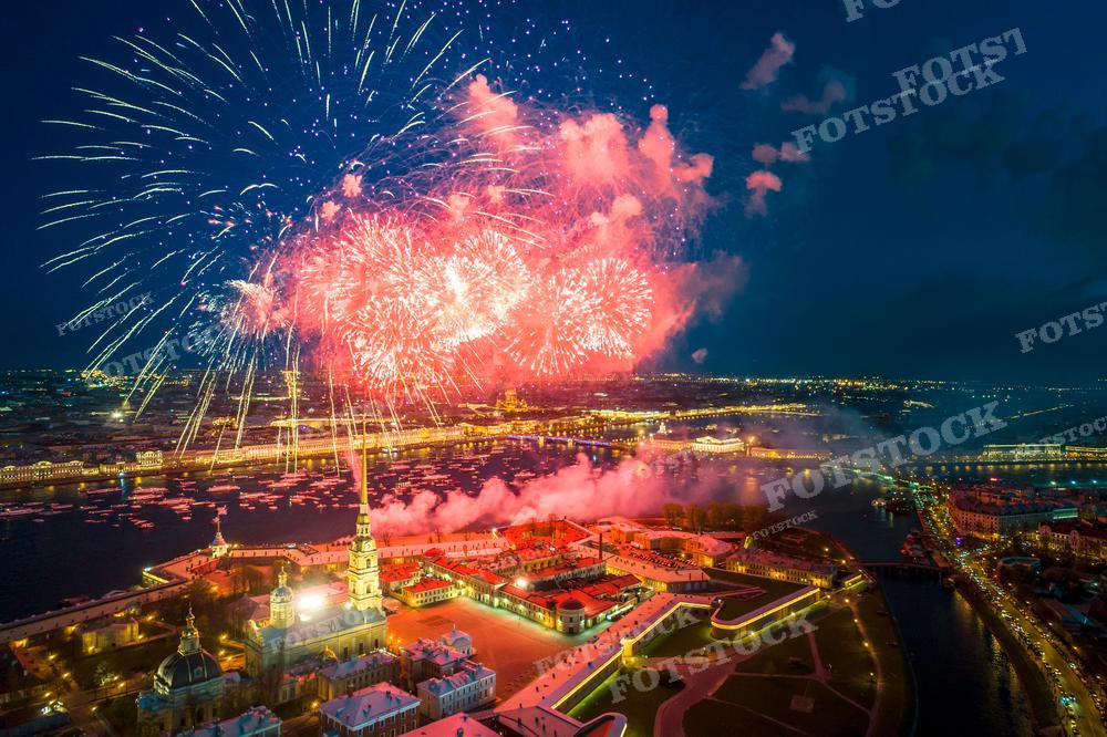 На фотографии запечатлен ночной вид Санкт-Петербурга во время праздничного салюта. Фейерверк вспыхивает яркими красками над Петропавловской крепостью, расположенной на берегу реки Невы. Ночное освещение города и отражение огней в воде создают волшебную атмосферу. Эта фотография идеально подойдет для использования в материалах, посвященных праздникам и фестивалям, для туристической рекламы, а также может быть использована в качестве постера или картины.